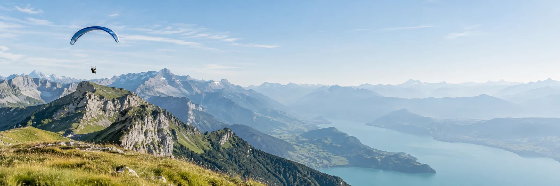 A paraglider suspended above an Alpine ridge and mountain valley